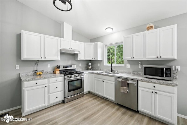 2660 N Jasper Dr, Wasilla, AK 99654 - kitchen with stainless steel appliances, under cabinet range hood, vaulted ceiling, white cabinets, and light wood finished floors