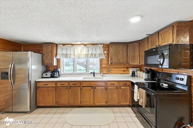 34035 Keystone Dr, Soldotna, AK 99669 - kitchen with black appliances, a textured ceiling, light countertops, brown cabinets, and light tile patterned flooring