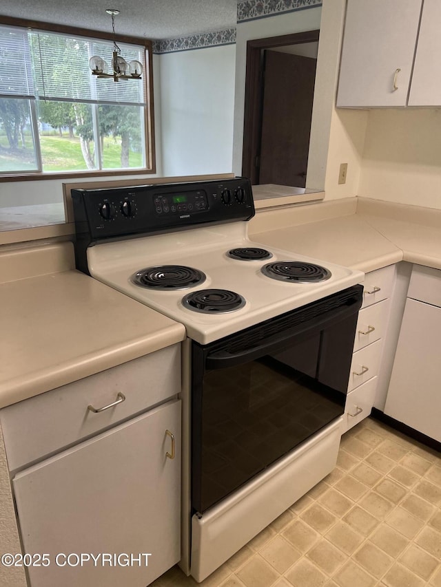 302 Sweetgale Ct # 302, Anchorage, AK 99518 - kitchen with electric range, light countertops, white cabinets, and a chandelier