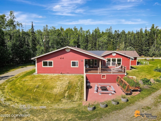 23324 Greatland Dr, Chugiak, AK 99577 - view of front of property with a front yard, an outdoor fire pit, a deck, a view of trees, and a patio