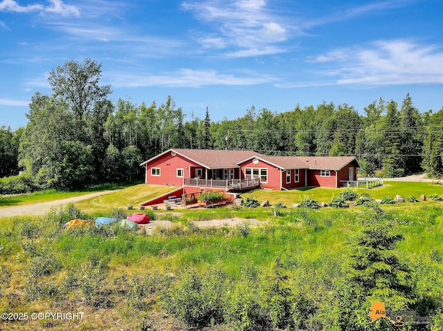 23324 Greatland Dr, Chugiak, AK 99577 - view of front facade featuring a wooden deck, a forest view, driveway, and a front lawn