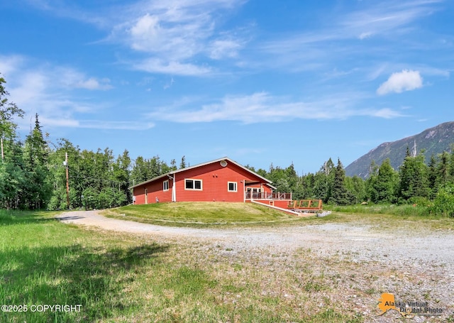 23324 Greatland Dr, Chugiak, AK 99577 - view of side of home featuring a deck with mountain view, a view of trees, and a yard