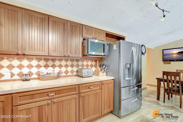 23324 Greatland Dr, Chugiak, AK 99577 - kitchen featuring appliances with stainless steel finishes, light tile patterned floors, decorative backsplash, light countertops, and lofted ceiling