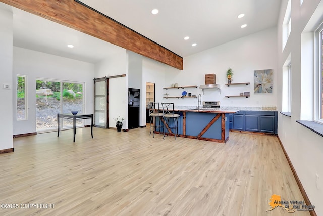 3528 S Mills Ct, Big Lake, AK 99623 - kitchen with open shelves, blue cabinets, high vaulted ceiling, a barn door, and a kitchen bar