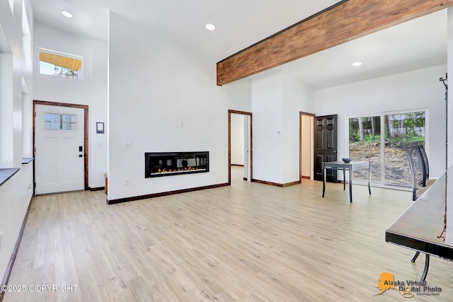 3528 S Mills Ct, Big Lake, AK 99623 - unfurnished living room with a towering ceiling, light wood-style floors, a glass covered fireplace, recessed lighting, and beamed ceiling