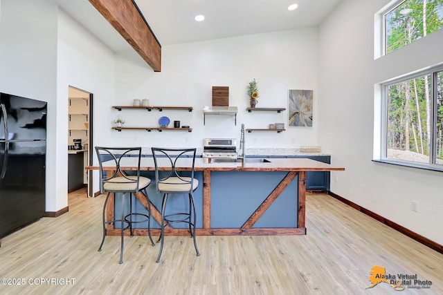 3528 S Mills Ct, Big Lake, AK 99623 - kitchen featuring freestanding refrigerator, light wood-style floors, a kitchen bar, open shelves, and stainless steel stove