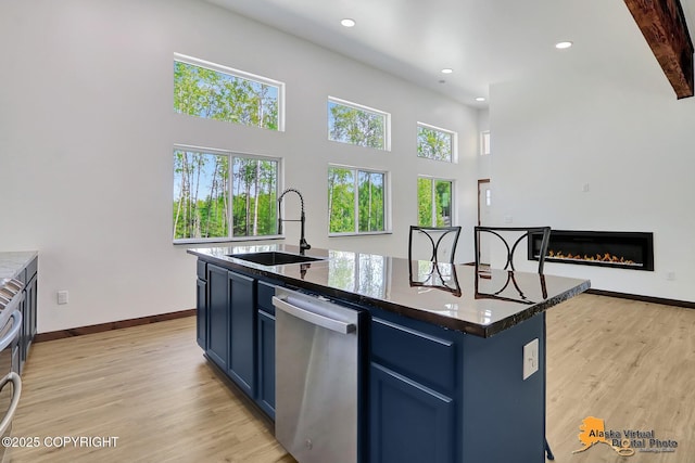 3528 S Mills Ct, Big Lake, AK 99623 - kitchen featuring stainless steel dishwasher, blue cabinets, light wood-style floors, recessed lighting, and a glass covered fireplace
