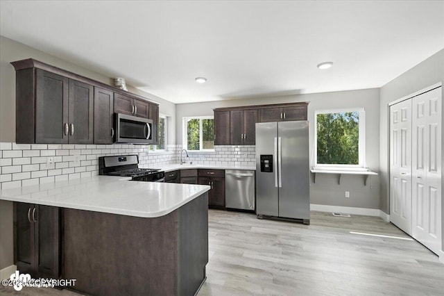 2740 S Rue De La Paix Loop, Wasilla, AK 99623 - kitchen with appliances with stainless steel finishes, dark brown cabinetry, light countertops, backsplash, and light wood-style floors