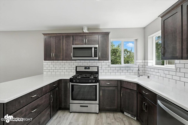 2740 S Rue De La Paix Loop, Wasilla, AK 99623 - kitchen with stainless steel appliances, backsplash, light countertops, dark brown cabinetry, and a peninsula