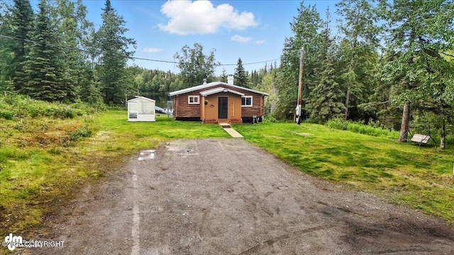48416 Bernice Lake Rd, Nikiski/North Kenai, AK 99611 - view of front of house with an outdoor structure, a forest view, a front lawn, and a chimney