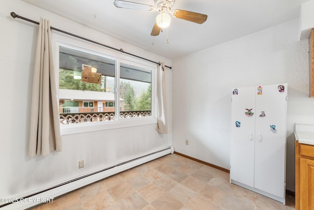8764 Trinity Dr, Juneau, AK 99801 - empty room with baseboard heating, healthy amount of natural light, a ceiling fan, and stone finish floors