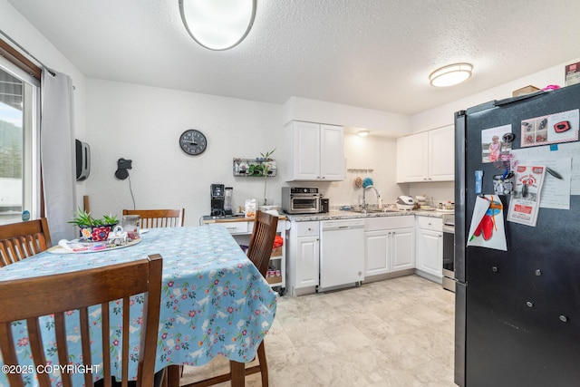 8764 Trinity Dr, Juneau, AK 99801 - kitchen with freestanding refrigerator, dishwasher, white cabinets, and a textured ceiling