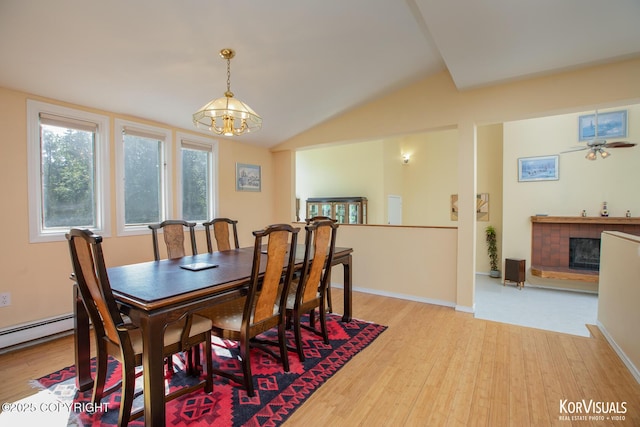 4450 Trapline Dr, Anchorage, AK 99516 - dining area featuring a fireplace with raised hearth, light wood finished floors, a chandelier, and vaulted ceiling