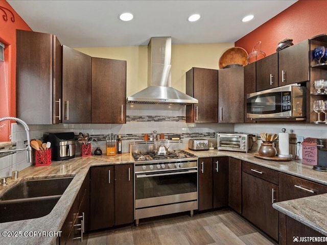 3872 N Charley Dr, Wasilla, AK 99654 - kitchen featuring wall chimney range hood, appliances with stainless steel finishes, tasteful backsplash, dark brown cabinets, and recessed lighting