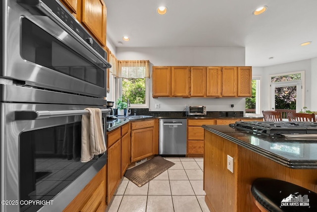250 Botanical Cir, Anchorage, AK 99515 - kitchen featuring stainless steel appliances, brown cabinetry, recessed lighting, light tile patterned floors, and dark stone counters