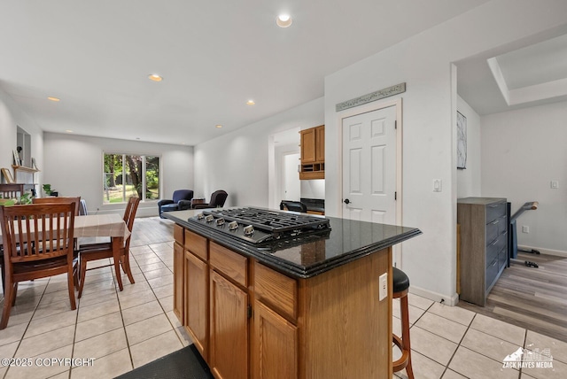 250 Botanical Cir, Anchorage, AK 99515 - kitchen with stainless steel gas stovetop, light tile patterned flooring, a kitchen island, brown cabinets, and a kitchen breakfast bar