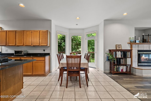 250 Botanical Cir, Anchorage, AK 99515 - kitchen featuring dark countertops, recessed lighting, brown cabinetry, a tile fireplace, and light tile patterned floors