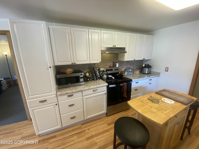 3411 Eagle Ave, Valdez, AK 99686 - kitchen with stainless steel appliances, under cabinet range hood, tasteful backsplash, light wood finished floors, and white cabinets