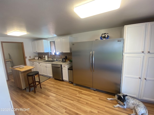 3411 Eagle Ave, Valdez, AK 99686 - kitchen featuring stainless steel appliances, white cabinetry, light countertops, light wood finished floors, and decorative backsplash