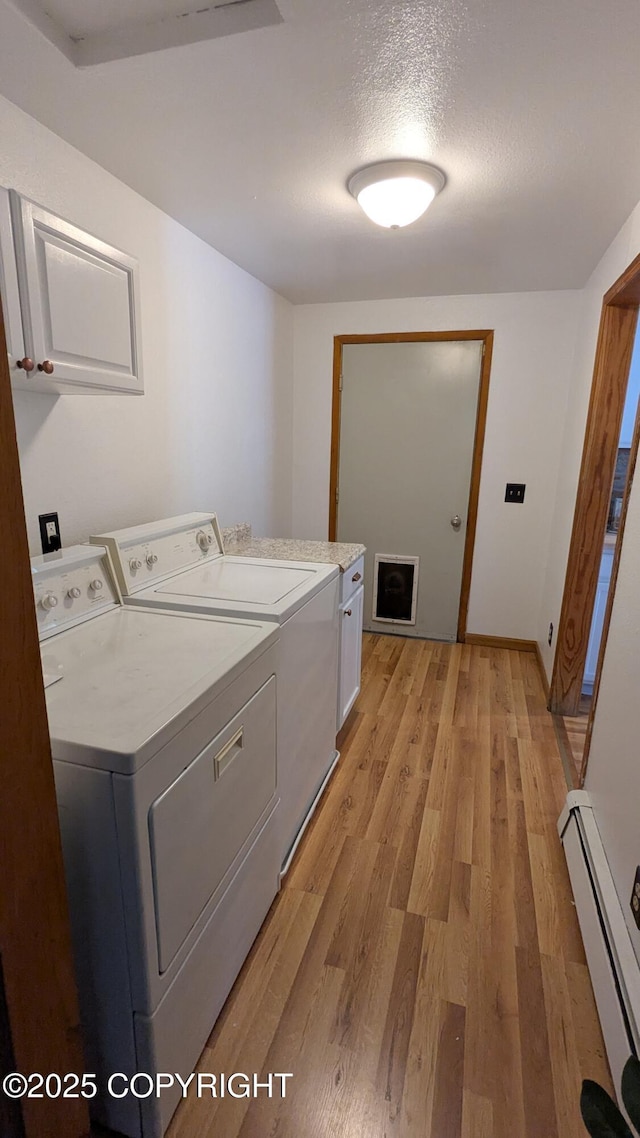 3411 Eagle Ave, Valdez, AK 99686 - laundry room featuring baseboard heating, cabinet space, washing machine and clothes dryer, light wood-style floors, and a textured ceiling