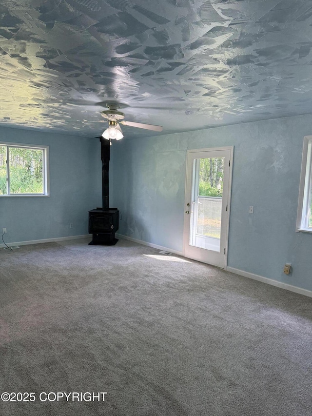 4100 W Peterson Bay Ct, Wasilla, AK 99623 - unfurnished living room with plenty of natural light, a wood stove, and carpet flooring