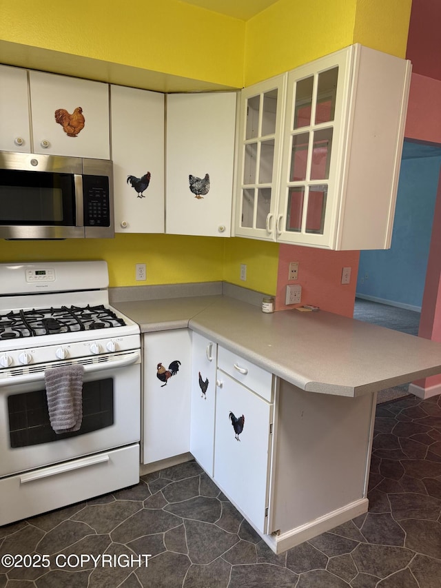 4100 W Peterson Bay Ct, Wasilla, AK 99623 - kitchen with stainless steel microwave, gas range gas stove, glass insert cabinets, a peninsula, and light countertops