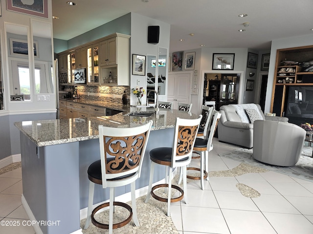 1240 Chinook Dr, Kenai, AK 99611 - kitchen with stainless steel microwave, light tile patterned floors, a breakfast bar area, glass insert cabinets, and stone countertops