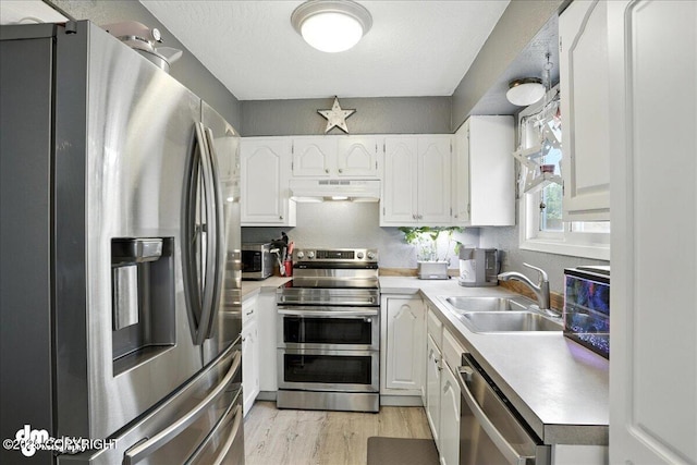 6260 Newt Dr, Anchorage, AK 99507 - kitchen with appliances with stainless steel finishes, under cabinet range hood, light wood-style flooring, white cabinetry, and light countertops