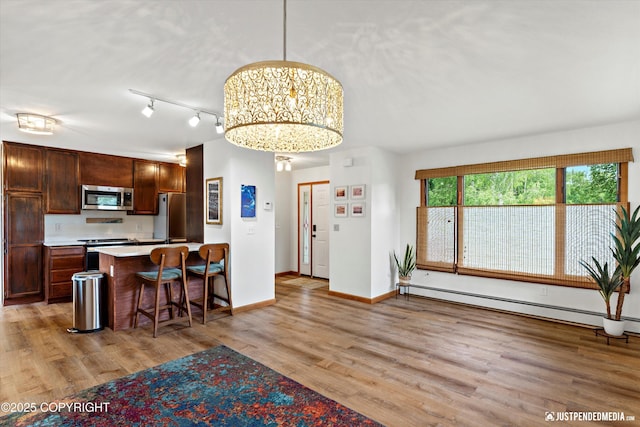 6922 Cutty Sark St, Anchorage, AK 99502 - kitchen featuring stainless steel appliances, a baseboard heating unit, a breakfast bar, light countertops, and light wood-style floors