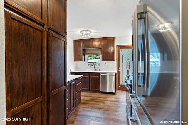 6922 Cutty Sark St, Anchorage, AK 99502 - kitchen with appliances with stainless steel finishes, light countertops, light wood finished floors, and decorative backsplash