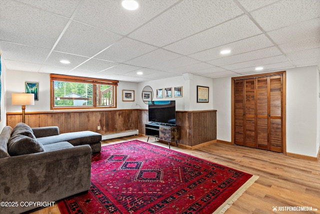 6922 Cutty Sark St, Anchorage, AK 99502 - living room featuring a baseboard radiator, a paneled ceiling, wood finished floors, a wainscoted wall, and wooden walls