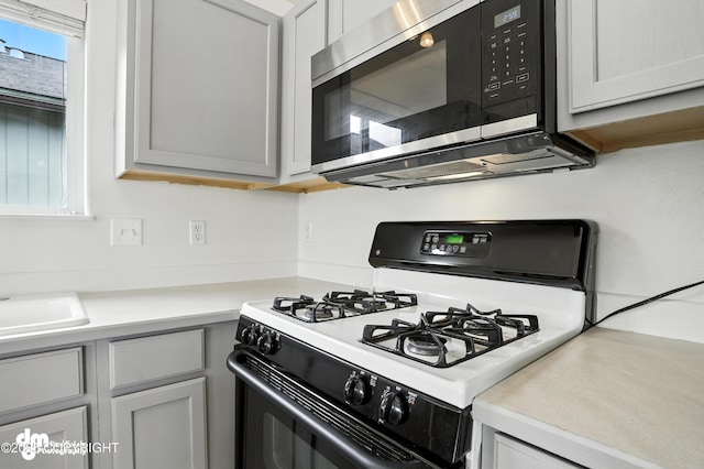 9380 Sea Parrot Cir, Anchorage, AK 99515 - kitchen featuring gas range, stainless steel microwave, light countertops, and gray cabinetry
