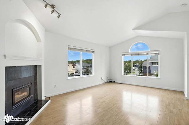 9380 Sea Parrot Cir, Anchorage, AK 99515 - unfurnished living room with lofted ceiling, a tile fireplace, and wood finished floors