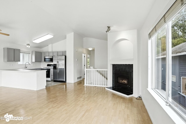 9380 Sea Parrot Cir, Anchorage, AK 99515 - kitchen featuring stainless steel appliances, gray cabinetry, a fireplace, lofted ceiling, and light wood finished floors
