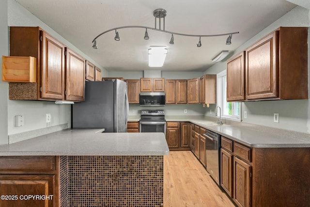 40800 Lopez Ave, Soldotna, AK 99669 - kitchen featuring appliances with stainless steel finishes, light wood-type flooring, a peninsula, light countertops, and brown cabinetry