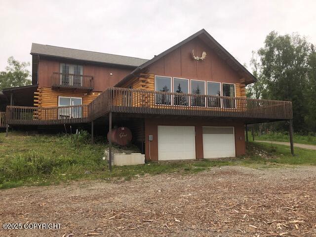 4033 W Sunrise Rd, Wasilla, AK 99623 - rear view of property featuring dirt driveway, log exterior, an attached garage, and a wooden deck