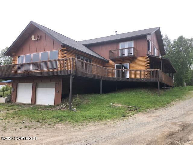 4033 W Sunrise Rd, Wasilla, AK 99623 - back of house featuring log exterior, an attached garage, and driveway
