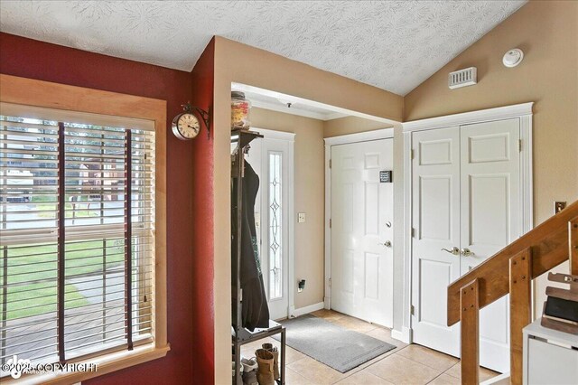 1801 Rebel Ridge Dr, Anchorage, AK 99504 - entryway with light tile patterned flooring, lofted ceiling, and a textured ceiling