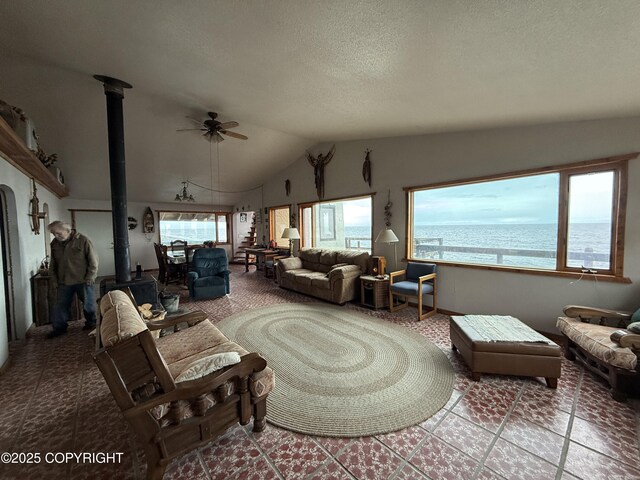 25646 Hawks Beach Rem SW, Anchor Point, AK 99556 - living area with a wood stove, ceiling fan, lofted ceiling, a water view, and a textured ceiling