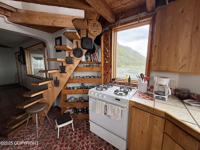 25646 Hawks Beach Rem SW, Anchor Point, AK 99556 - kitchen featuring gas range gas stove, tile countertops, open shelves, beamed ceiling, and arched walkways