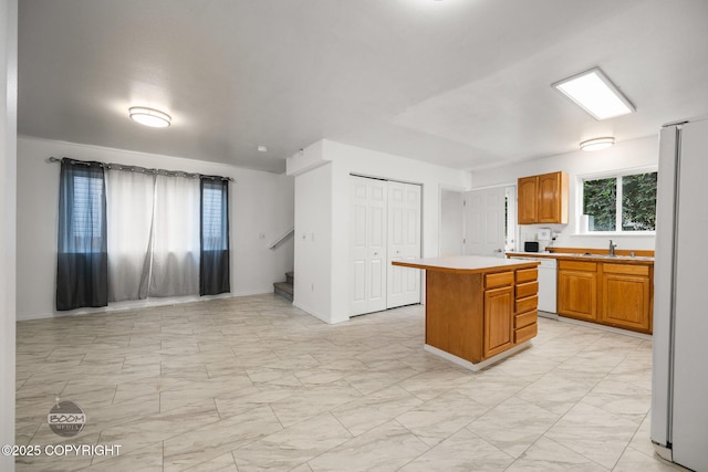 5622 E 4th Ave Unit 12, Anchorage, AK 99504 - kitchen with white appliances, light marble finish flooring, a center island, light countertops, and brown cabinetry