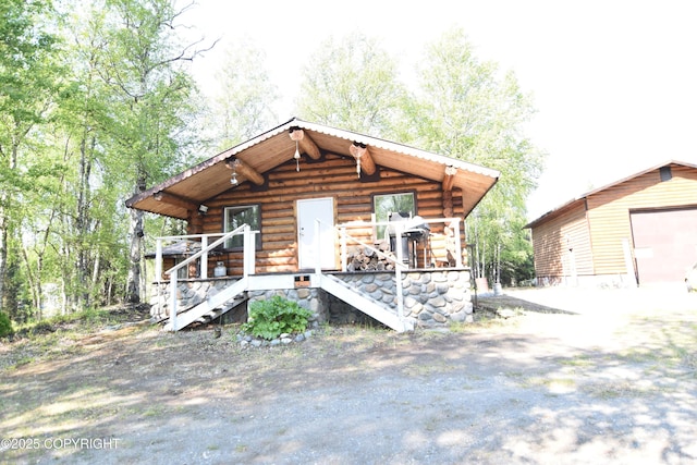 36544 St Theresa Rd, Soldotna, AK 99669 - log cabin with log exterior, driveway, a detached garage, covered porch, and an outbuilding