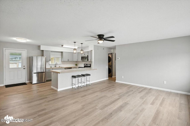 4335 E 6th Ave, Anchorage, AK 99508 - unfurnished living room featuring estacked washer and dryer, a textured ceiling, light wood-type flooring, and ceiling fan