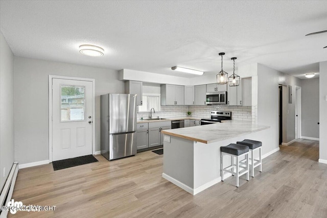 4335 E 6th Ave, Anchorage, AK 99508 - kitchen featuring stainless steel appliances, gray cabinetry, a baseboard heating unit, a peninsula, and a kitchen breakfast bar