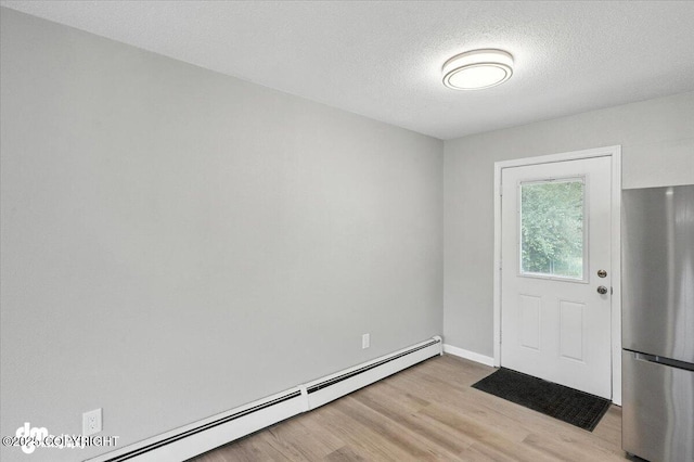 4335 E 6th Ave, Anchorage, AK 99508 - foyer entrance with baseboard heating, light wood-style floors, and a textured ceiling
