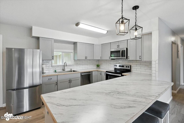 4335 E 6th Ave, Anchorage, AK 99508 - kitchen featuring stainless steel appliances, light wood-type flooring, gray cabinetry, and a peninsula