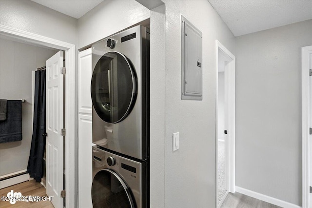 4335 E 6th Ave, Anchorage, AK 99508 - laundry area featuring stacked washing machine and dryer, light wood finished floors, and electric panel