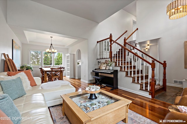 15250 Evergreen Ridge St, Anchorage, AK 99516 - living room featuring arched walkways, a chandelier, wood finished floors, and stairs