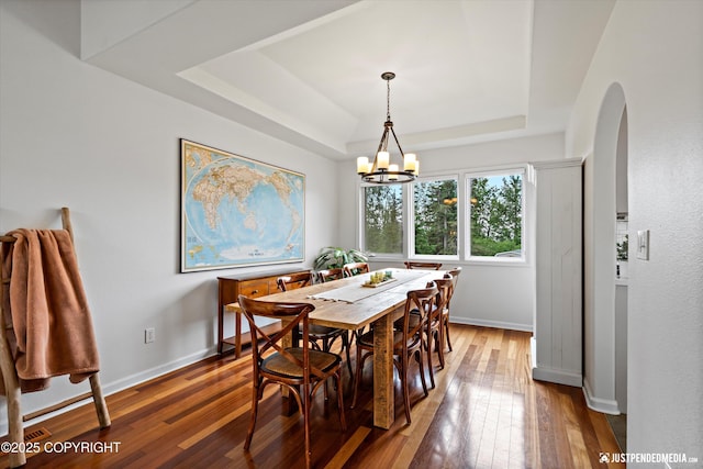 15250 Evergreen Ridge St, Anchorage, AK 99516 - dining room featuring a raised ceiling, arched walkways, wood-type flooring, and a chandelier