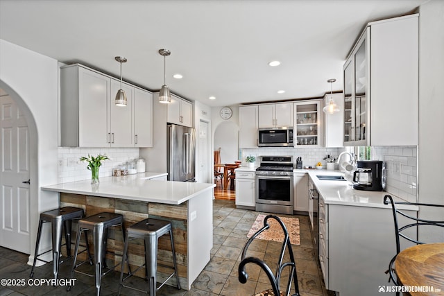 15250 Evergreen Ridge St, Anchorage, AK 99516 - kitchen with stainless steel appliances, a peninsula, backsplash, a kitchen bar, and recessed lighting